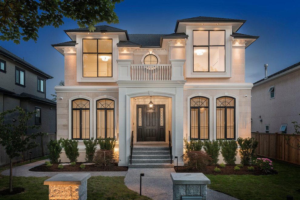Large two-storey white house exterior in Vancouver with stone veneer, a hip roof and a shingle roof.