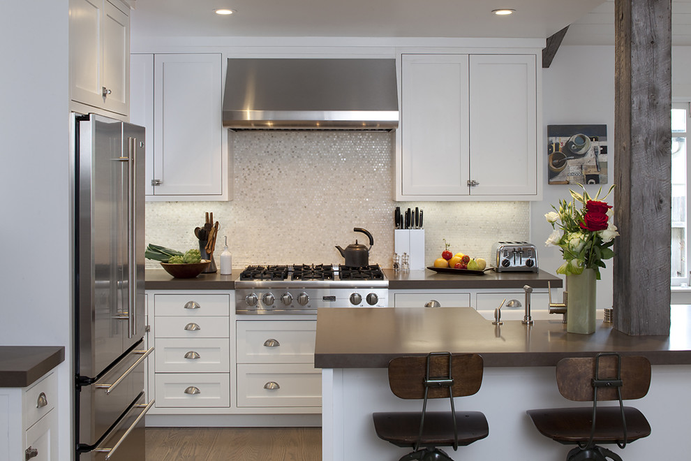 Photo of a traditional kitchen in San Francisco with stainless steel appliances, a farmhouse sink, shaker cabinets, white cabinets, mosaic tile splashback and metallic splashback.