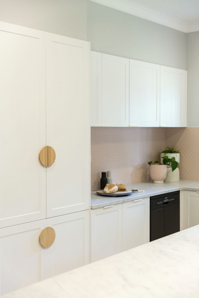 Small scandinavian l-shaped eat-in kitchen in Melbourne with an undermount sink, recessed-panel cabinets, white cabinets, quartz benchtops, pink splashback, mosaic tile splashback, black appliances, medium hardwood floors, with island and white benchtop.