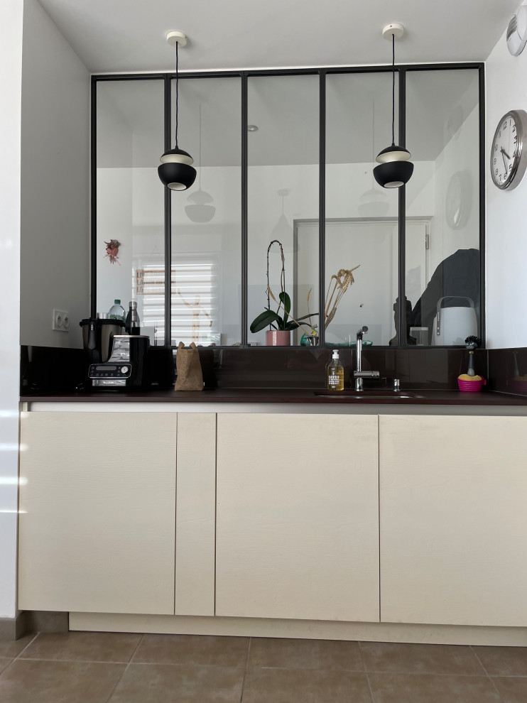 Immagine di una cucina minimalista di medie dimensioni con lavello integrato, ante a filo, ante in acciaio inossidabile, top in quarzite, paraspruzzi nero, paraspruzzi con piastrelle di vetro, elettrodomestici colorati, pavimento in cementine, pavimento grigio e top marrone