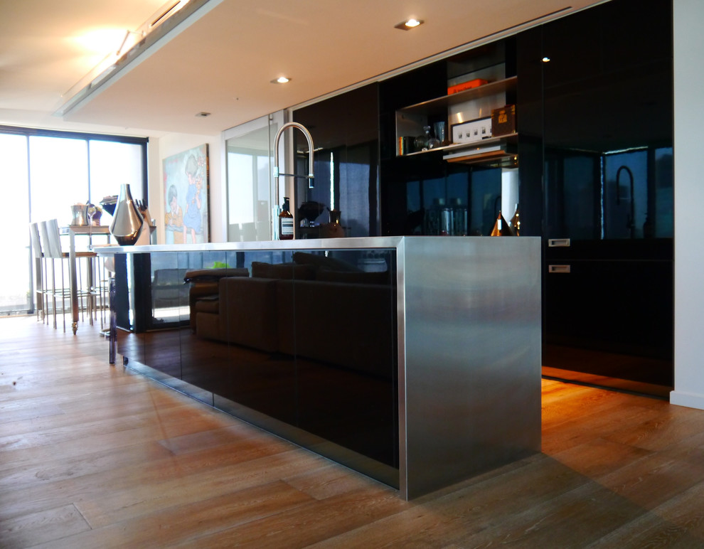 Photo of a contemporary galley eat-in kitchen in Melbourne with an integrated sink, flat-panel cabinets, black cabinets, stainless steel benchtops and stainless steel appliances.