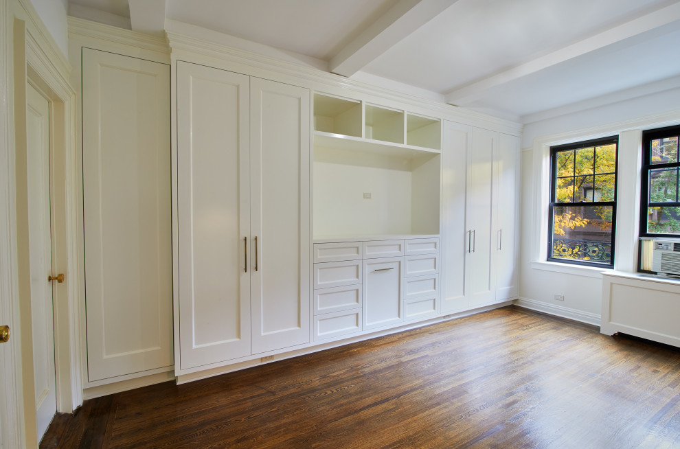 Photo of a large traditional master bedroom in New York with white walls, dark hardwood floors and brown floor.
