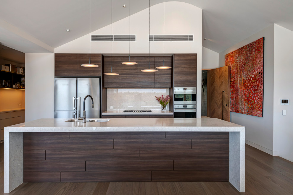 Cette photo montre une grande cuisine ouverte tendance en bois foncé avec un plan de travail en quartz modifié, un électroménager en acier inoxydable, îlot et un sol marron.