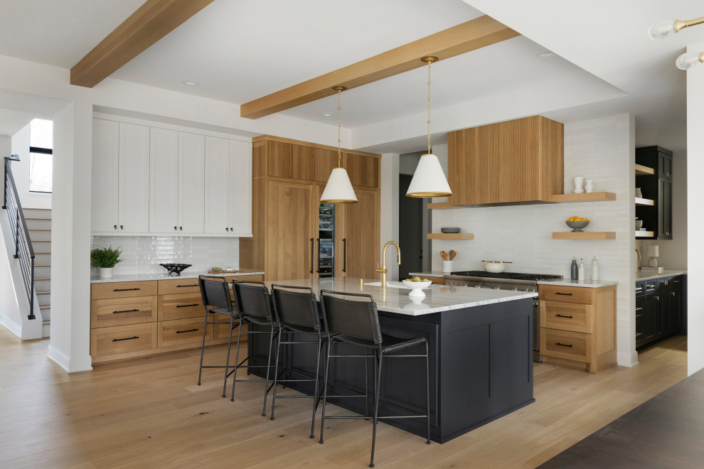 This is an example of a transitional kitchen in Minneapolis with a drop-in sink, light wood cabinets, quartz benchtops, stainless steel appliances, light hardwood floors, with island and vaulted.