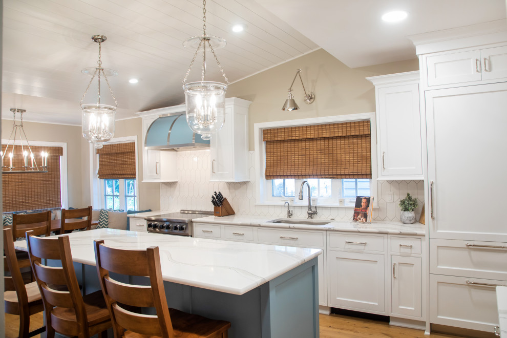 Inspiration for a large transitional u-shaped eat-in kitchen in Milwaukee with an undermount sink, recessed-panel cabinets, white cabinets, quartz benchtops, white splashback, porcelain splashback, stainless steel appliances, medium hardwood floors, with island, brown floor, white benchtop and timber.