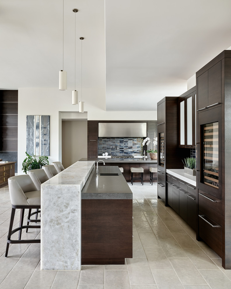 This is an example of a large modern open plan kitchen in Phoenix with an undermount sink, flat-panel cabinets, dark wood cabinets, solid surface benchtops, metallic splashback, ceramic splashback, stainless steel appliances, white floor, white benchtop and with island.