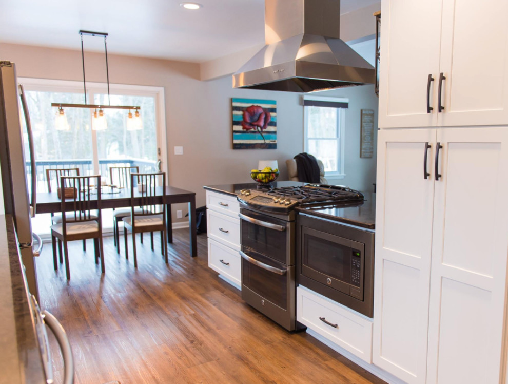 Eat-in kitchen - mid-sized transitional galley medium tone wood floor and brown floor eat-in kitchen idea with an undermount sink, shaker cabinets, white cabinets, marble countertops, metallic backsplash, mosaic tile backsplash, stainless steel appliances and a peninsula