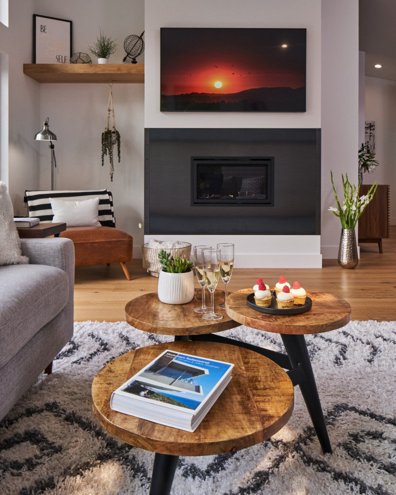 Example of a mid-sized minimalist open concept light wood floor, brown floor and vaulted ceiling living room design in Other with white walls, a hanging fireplace, a metal fireplace and a wall-mounted tv