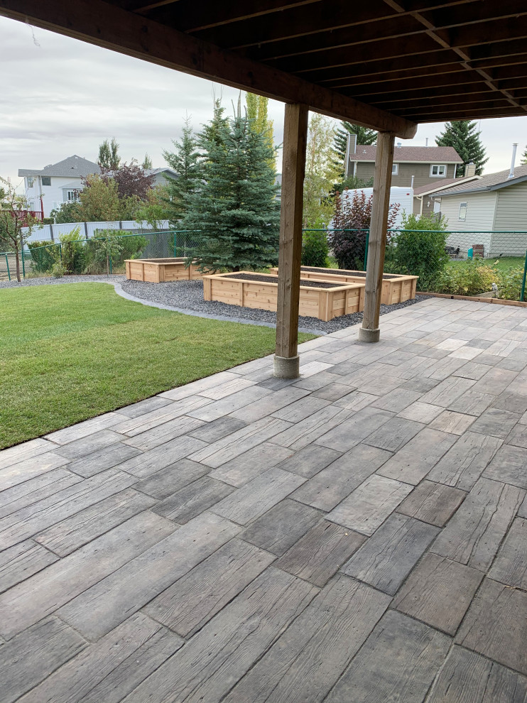 Medium sized traditional back patio in Calgary with a potted garden, decomposed granite and a roof extension.