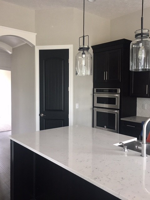 Large transitional dark wood floor kitchen photo in Columbus with a farmhouse sink, dark wood cabinets, quartz countertops, white backsplash, ceramic backsplash, stainless steel appliances, recessed-panel cabinets and an island
