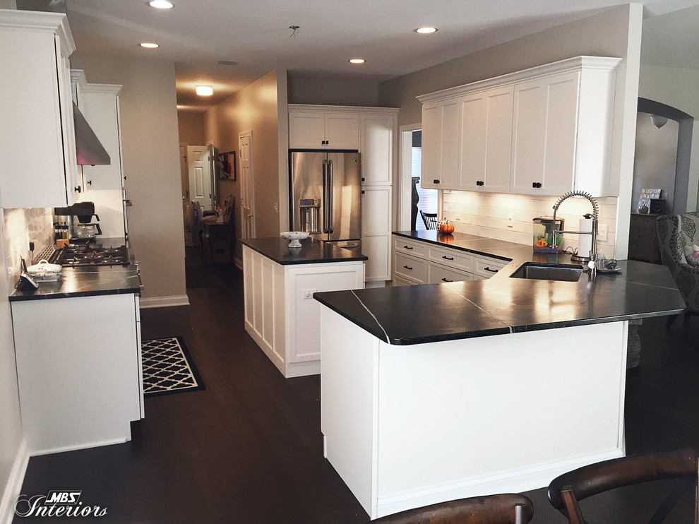 Inspiration for a mid-sized transitional u-shaped dark wood floor and brown floor eat-in kitchen remodel with an undermount sink, recessed-panel cabinets, white cabinets, soapstone countertops, white backsplash, subway tile backsplash, stainless steel appliances and an island