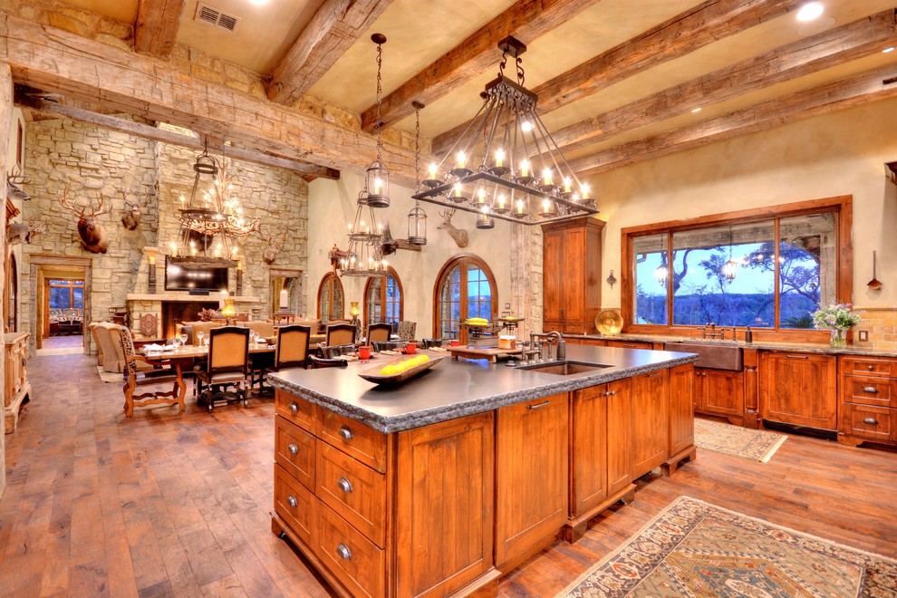 Example of a mountain style u-shaped medium tone wood floor eat-in kitchen design in Austin with a farmhouse sink, beaded inset cabinets, medium tone wood cabinets, granite countertops, stainless steel appliances and an island