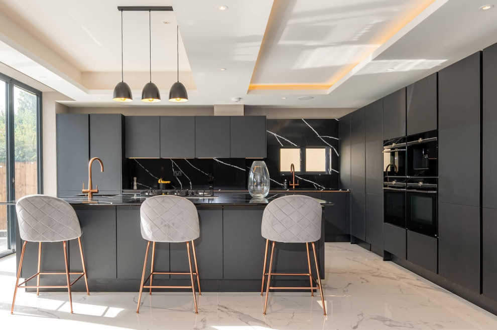 Inspiration for a large modern l-shaped marble floor and tray ceiling open concept kitchen remodel in Hertfordshire with flat-panel cabinets, black backsplash, black appliances, an island and black countertops