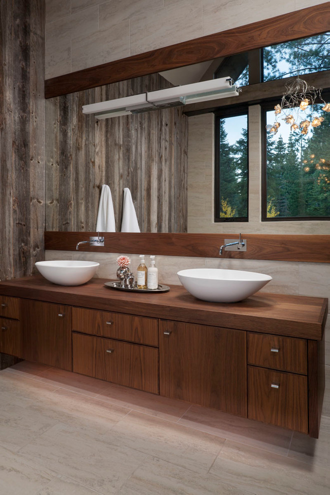 Country bathroom in San Francisco with a vessel sink, flat-panel cabinets, dark wood cabinets, wood benchtops, beige tile and beige walls.