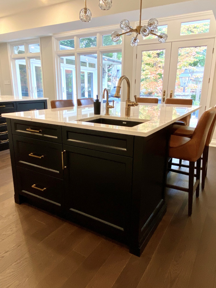 Large transitional medium tone wood floor kitchen photo in Toronto with an undermount sink, recessed-panel cabinets, white cabinets, quartz countertops, white backsplash, porcelain backsplash, paneled appliances, two islands and white countertops