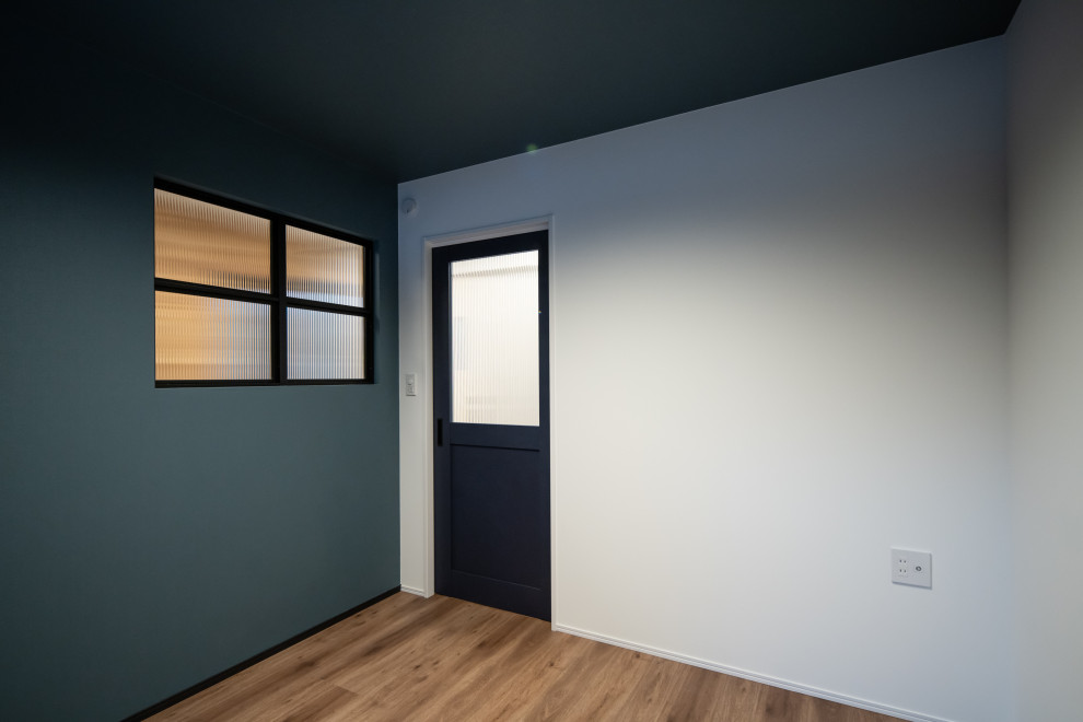 Cette image montre une chambre parentale minimaliste avec un mur vert, un sol en contreplaqué, un sol marron et un plafond en papier peint.