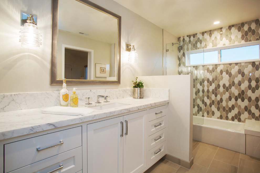 Inspiration for a mid-sized transitional bathroom in Orange County with shaker cabinets, white cabinets, an alcove tub, a shower/bathtub combo, a one-piece toilet, gray tile, porcelain tile, grey walls, porcelain floors, a drop-in sink, marble benchtops, grey floor and an open shower.