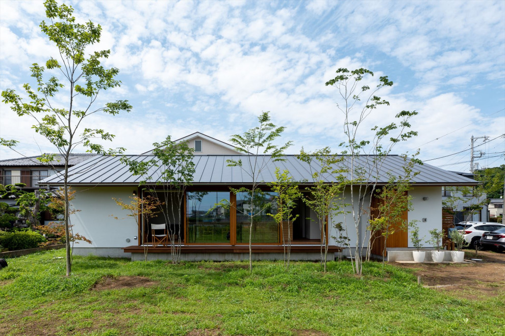 Modelo de fachada blanca de estilo zen de dos plantas con tejado de metal