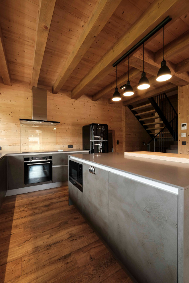 Inspiration for a large rustic l-shaped open plan kitchen in Lyon with a submerged sink, all styles of cabinet, grey cabinets, composite countertops, glass sheet splashback, stainless steel appliances, laminate floors, an island, brown floors, grey worktops and a wood ceiling.