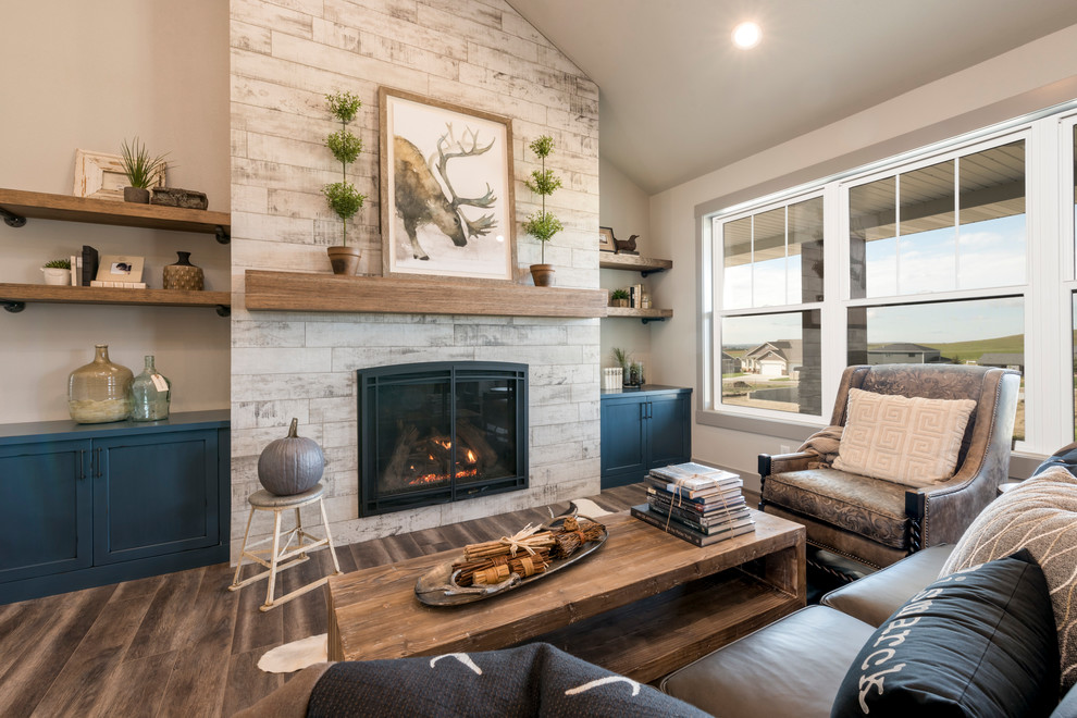 Inspiration for a mid-sized country open concept living room in Other with grey walls, vinyl floors, a standard fireplace, a tile fireplace surround, a concealed tv and brown floor.