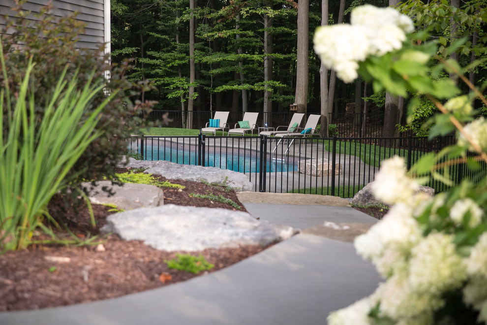 Inspiration for a mid-sized contemporary backyard concrete and custom-shaped pool remodel in Grand Rapids