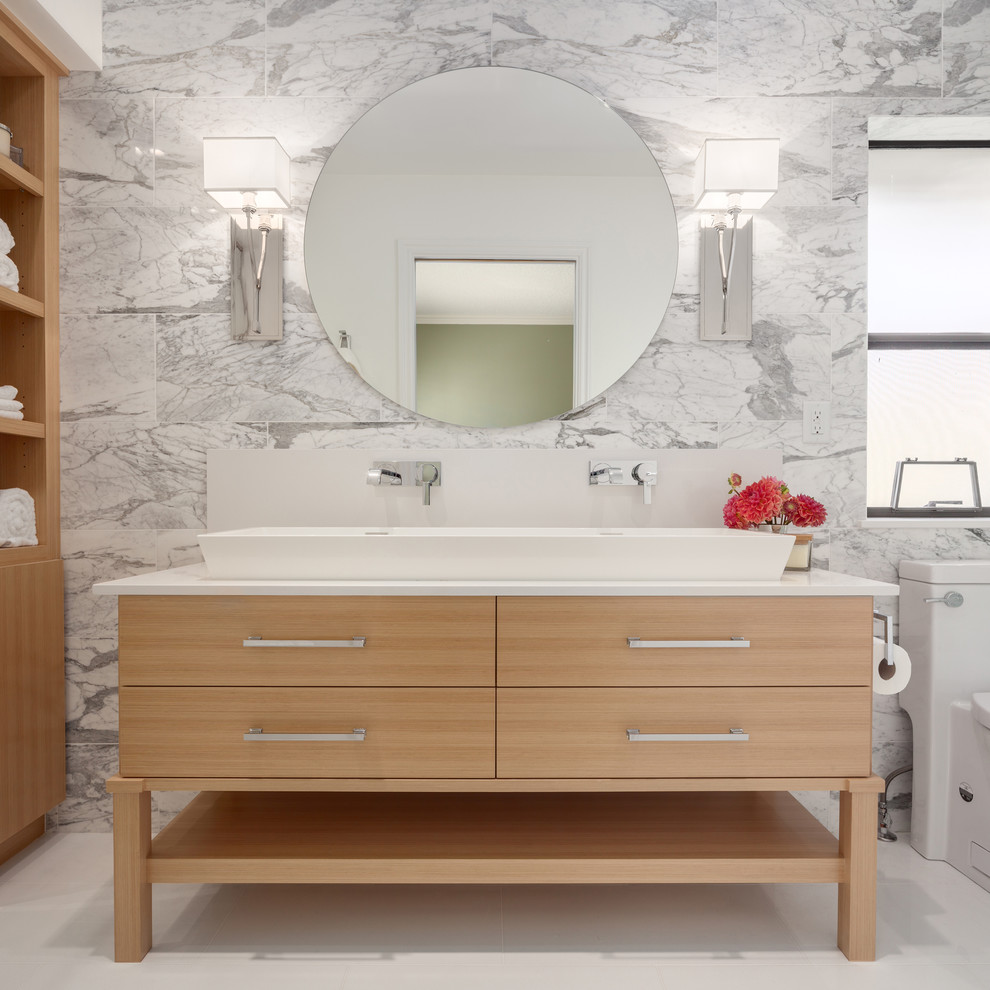 Photo of a large transitional master bathroom in Vancouver with a trough sink, flat-panel cabinets, light wood cabinets, a one-piece toilet, multi-coloured tile, stone tile, multi-coloured walls, porcelain floors, engineered quartz benchtops and an alcove shower.