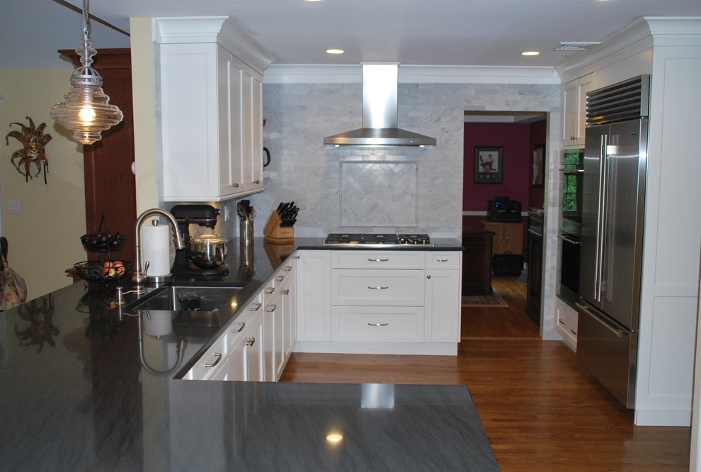Inspiration for a large transitional u-shaped medium tone wood floor and brown floor open concept kitchen remodel with an undermount sink, recessed-panel cabinets, white cabinets, granite countertops, gray backsplash, marble backsplash, stainless steel appliances and a peninsula