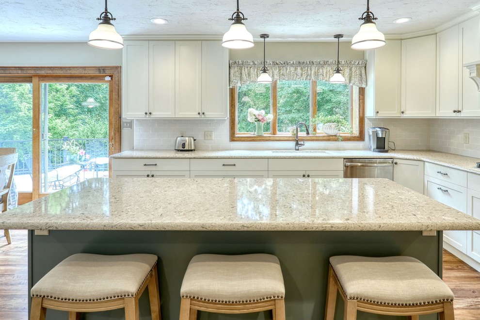 Kitchen - transitional vinyl floor and brown floor kitchen idea with an undermount sink, white cabinets, quartz countertops, white backsplash, subway tile backsplash, stainless steel appliances, an island and beige countertops