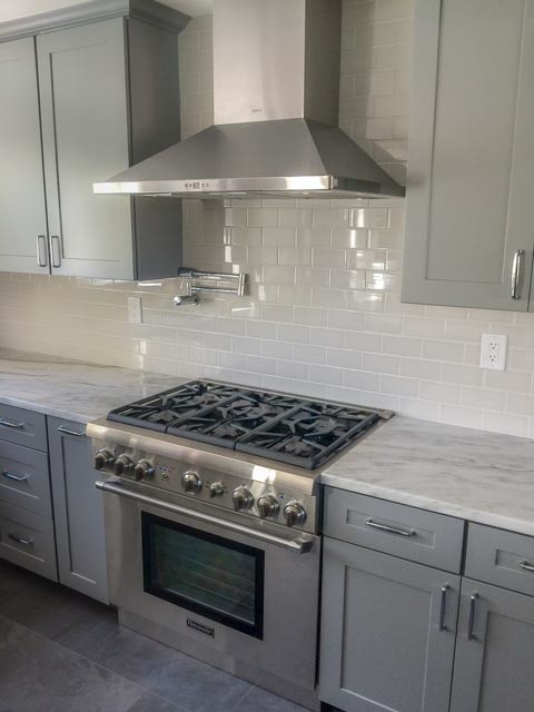 Mid-sized contemporary l-shaped open plan kitchen in San Francisco with a double-bowl sink, shaker cabinets, grey cabinets, granite benchtops, white splashback, subway tile splashback, stainless steel appliances, porcelain floors and with island.