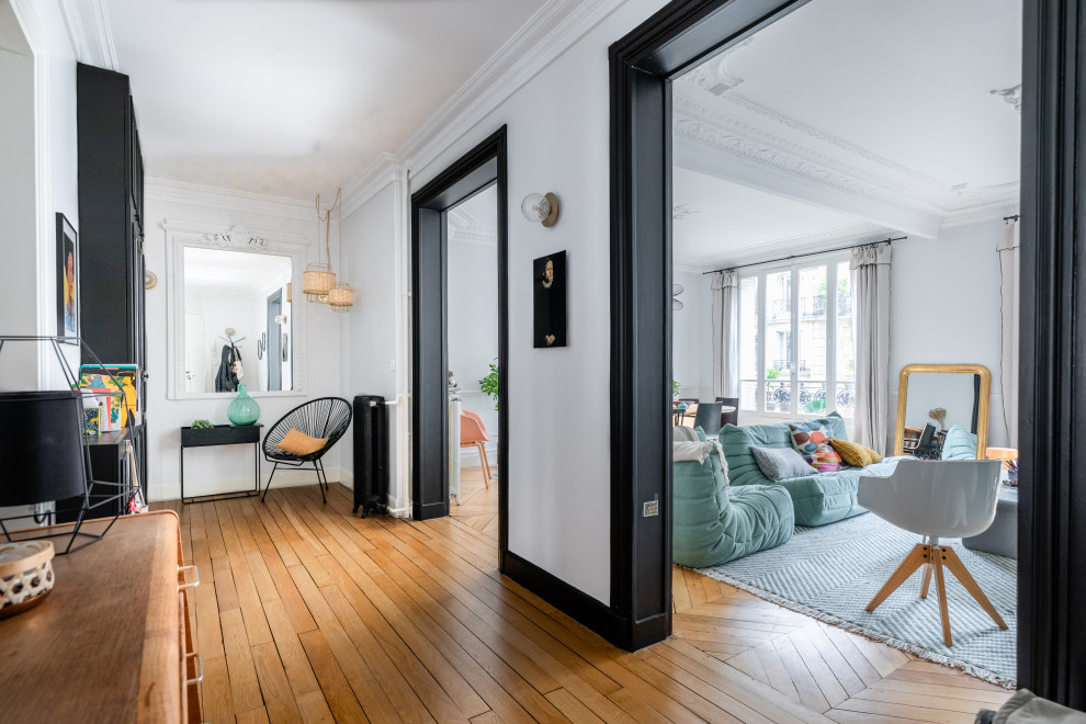 Großer Moderner Flur mit weißer Wandfarbe, hellem Holzboden und braunem Boden in Paris