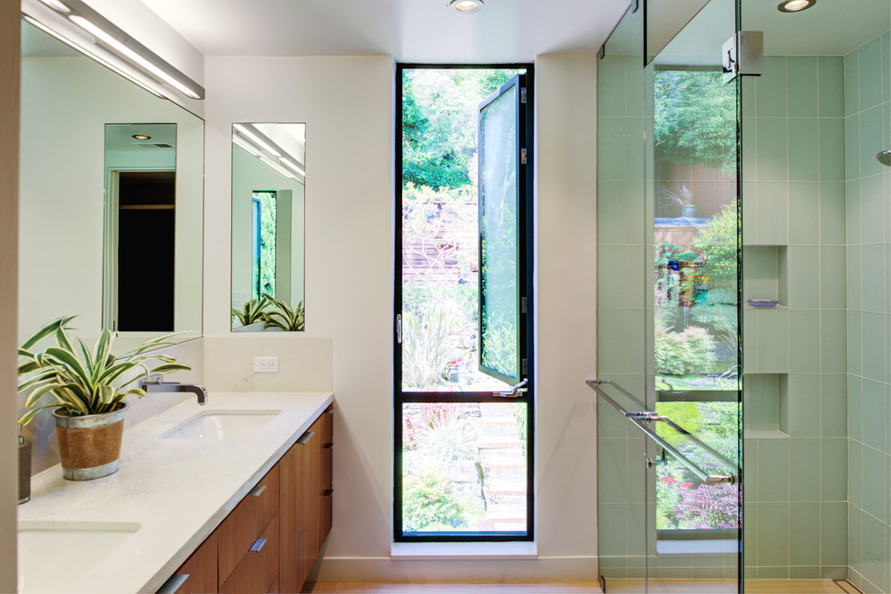 Small contemporary master bathroom in San Francisco with flat-panel cabinets, medium wood cabinets, a corner shower, glass tile, white walls, porcelain floors, an undermount sink, engineered quartz benchtops, a hinged shower door, green tile, beige floor and white benchtops.