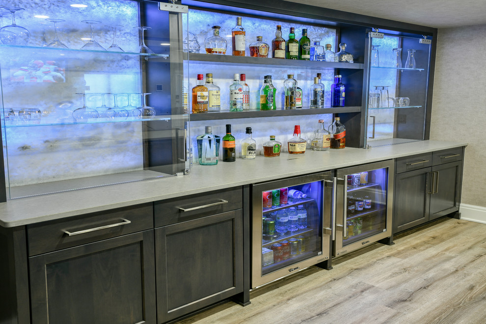 Inspiration for a large contemporary single-wall seated home bar in Cleveland with an undermount sink, shaker cabinets, dark wood cabinets, quartz benchtops, grey splashback, vinyl floors, beige floor and grey benchtop.