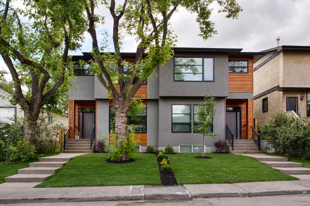 This is an example of a contemporary two-storey grey duplex exterior in Calgary with mixed siding.