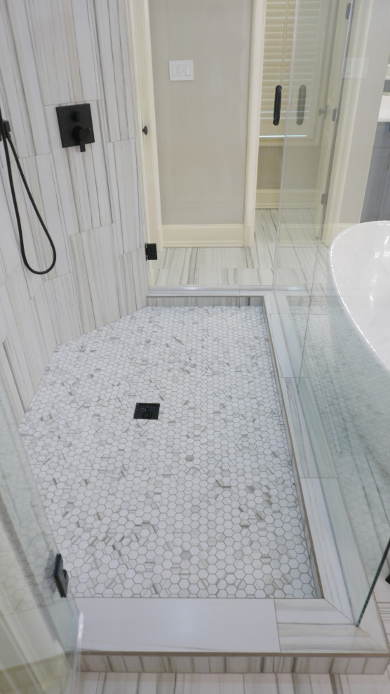 This is an example of a large transitional master bathroom in Other with shaker cabinets, blue cabinets, a freestanding tub, a double shower, a one-piece toilet, black and white tile, porcelain tile, grey walls, porcelain floors, an undermount sink, engineered quartz benchtops, multi-coloured floor, a hinged shower door, white benchtops, a niche, a single vanity and a built-in vanity.