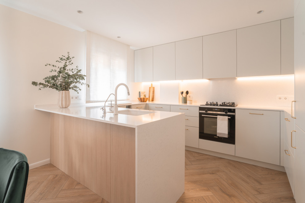 Inspiration for a contemporary u-shaped kitchen in Alicante-Costa Blanca with an undermount sink, flat-panel cabinets, white cabinets, black appliances, medium hardwood floors, a peninsula, brown floor and white benchtop.