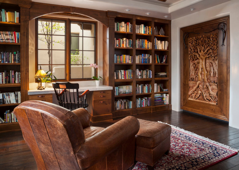 This is an example of a mid-sized traditional home office in Orange County with a library, white walls, dark hardwood floors and a built-in desk.