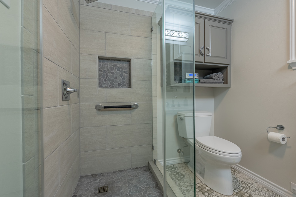 Small modern 3/4 bathroom in Austin with glass-front cabinets, grey cabinets, a corner shower, a two-piece toilet, beige walls, ceramic floors, a drop-in sink, granite benchtops, multi-coloured floor, a hinged shower door and white benchtops.