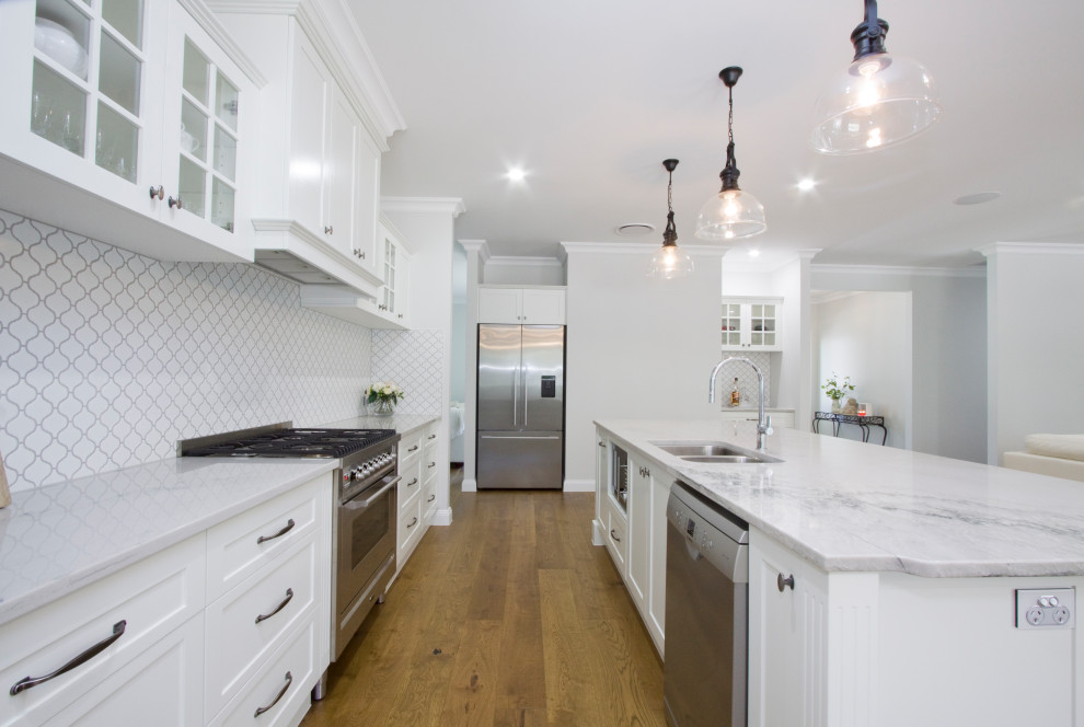 This is an example of a large traditional open plan kitchen in Sunshine Coast with an undermount sink, shaker cabinets, white cabinets, quartzite benchtops, mosaic tile splashback, stainless steel appliances and with island.