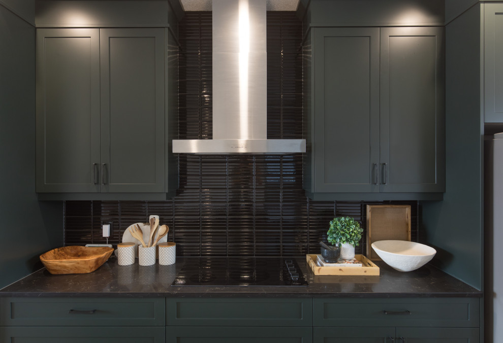 Immagine di un cucina con isola centrale country di medie dimensioni con ante in stile shaker, paraspruzzi nero, elettrodomestici in acciaio inossidabile, pavimento marrone e top nero