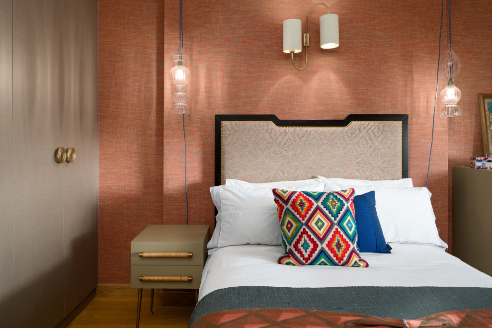 Imagen de dormitorio contemporáneo grande con parades naranjas, suelo de madera en tonos medios y papel pintado