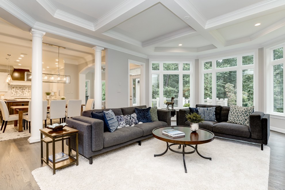 Photo of a large transitional open concept family room in DC Metro with grey walls, light hardwood floors, beige floor, no fireplace, a stone fireplace surround and no tv.