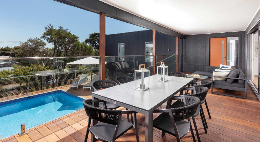 Photo of a contemporary first floor deck in Melbourne with a roof extension and glass railing.