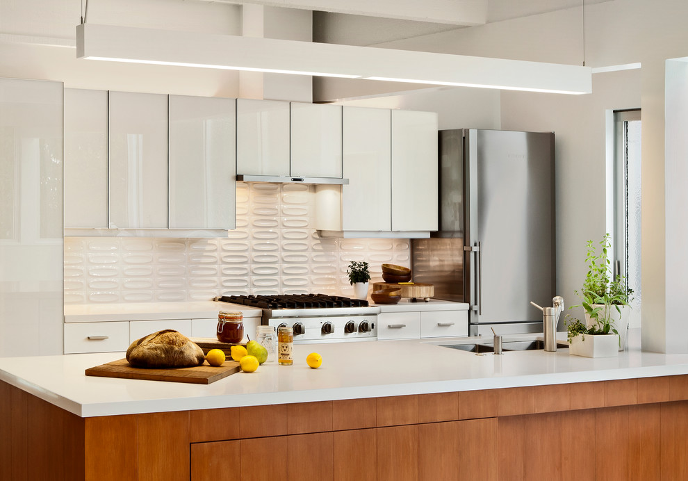 Photo of a midcentury galley kitchen in San Francisco with stainless steel appliances, a double-bowl sink, flat-panel cabinets, white cabinets and white splashback.