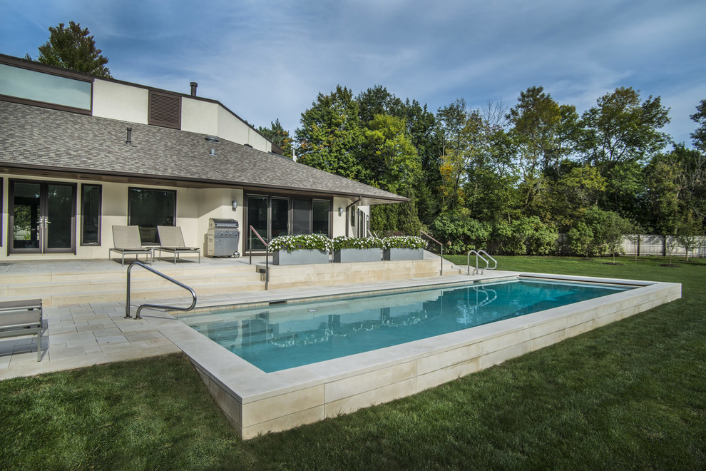 Example of a mid-sized minimalist backyard stone and rectangular pool design in Chicago