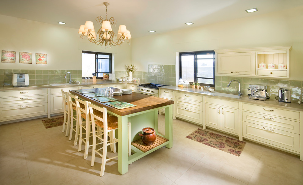 Traditional kitchen in Other with beige cabinets and green splashback.
