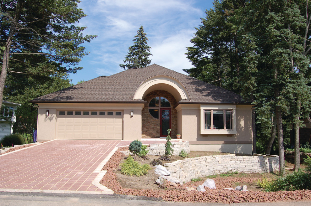Photo of a mid-sized one-storey stucco beige exterior in Other with a hip roof.