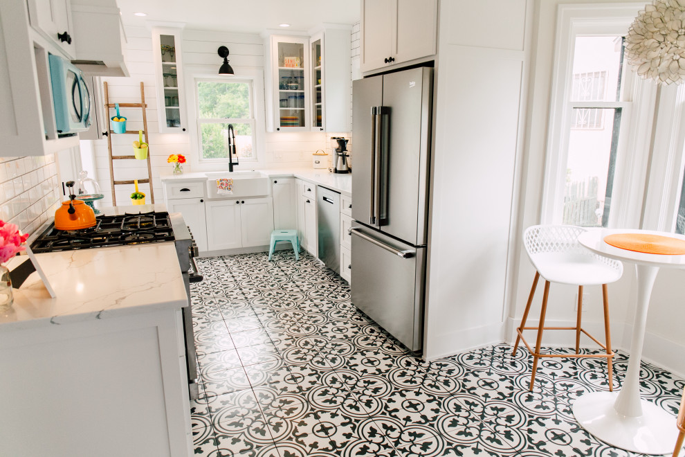 Inspiration for a small eclectic u-shaped separate kitchen in Seattle with a farmhouse sink, shaker cabinets, white cabinets, quartz benchtops, white splashback, ceramic splashback, stainless steel appliances, porcelain floors, no island, black floor and white benchtop.