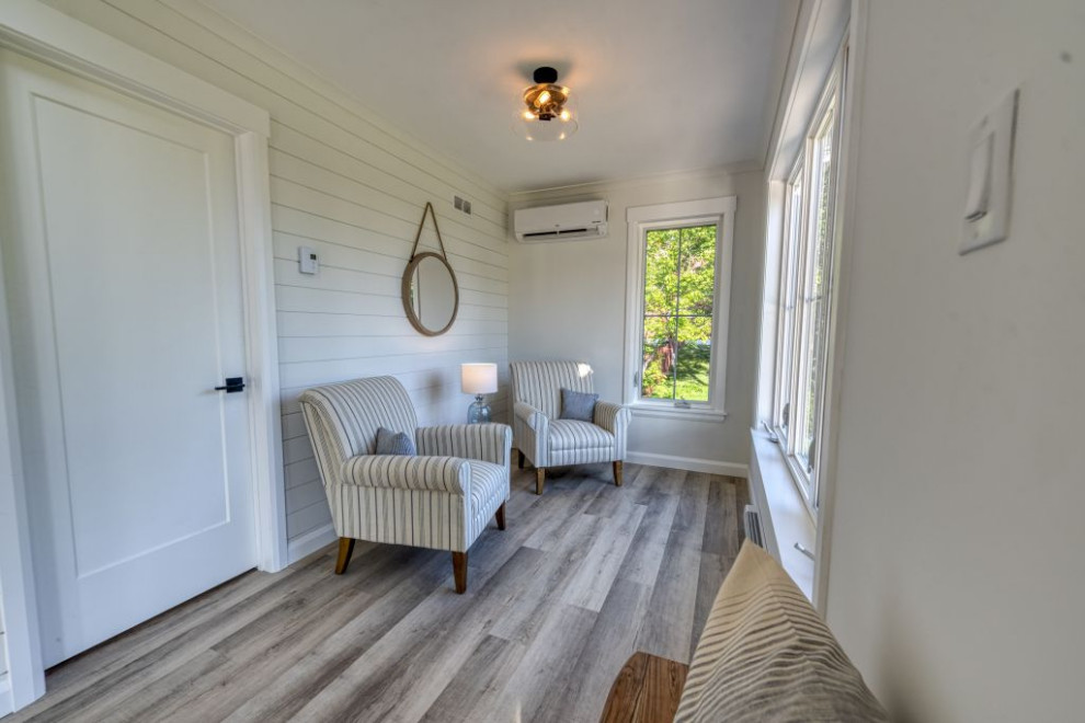 Ispirazione per un piccolo soggiorno stile marinaro stile loft con pareti bianche, pavimento in laminato e pavimento marrone