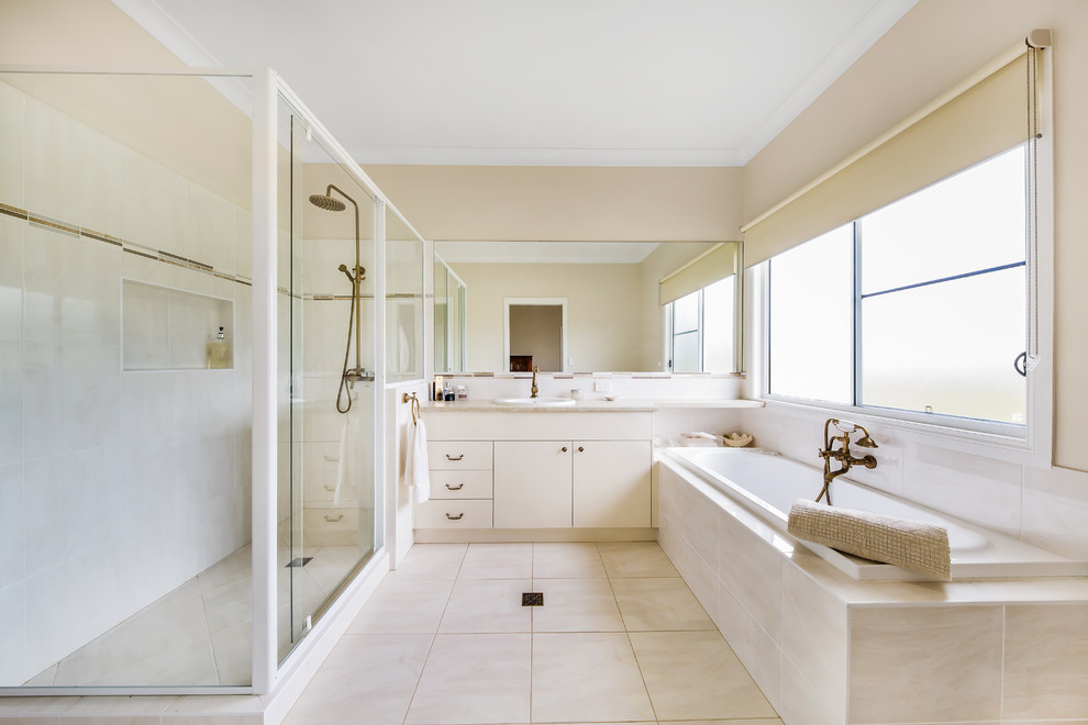 This is an example of a transitional master bathroom in Other with a drop-in tub, an alcove shower, beige walls, ceramic floors, a drop-in sink, beige floor, flat-panel cabinets, beige cabinets, beige tile and a sliding shower screen.