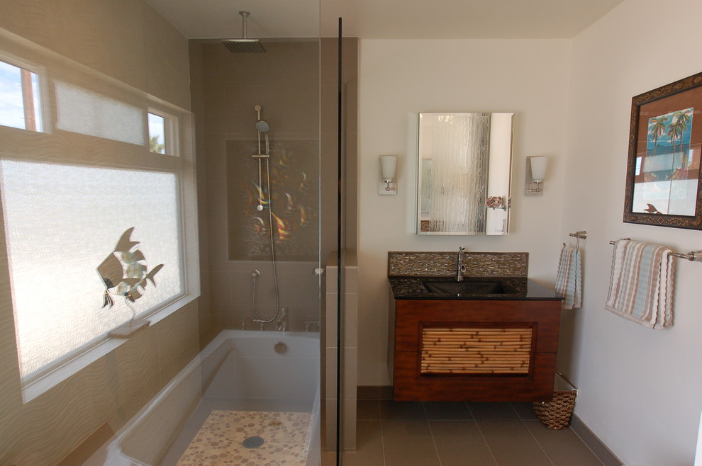 Design ideas for a mid-sized transitional master bathroom in San Diego with flat-panel cabinets, dark wood cabinets, beige tile, ceramic tile, glass benchtops, a drop-in tub, an alcove shower, a one-piece toilet, white walls, porcelain floors and an integrated sink.